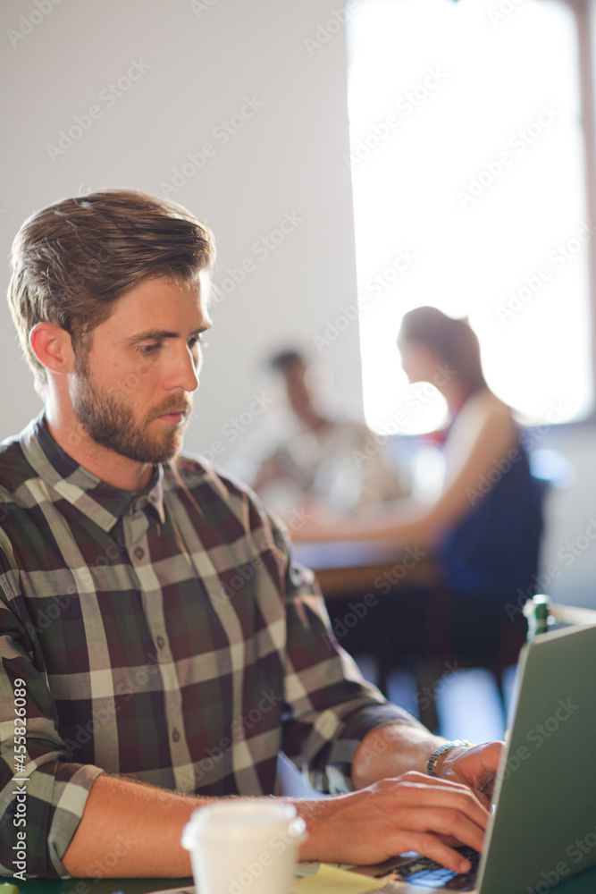 Fototapeta premium Casual businessman using laptop in office