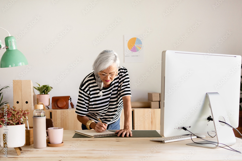 Senior businesswoman writing in a notebook on the desk Senior businesswoman writing in a notebook on the desk