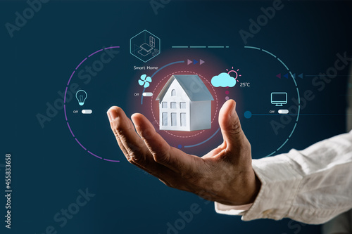 Businessman holding a house model with virtual screen of smart home automation application. Smart home controlling and Automation system technology of things