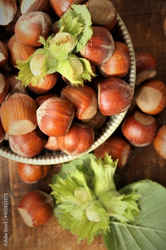 Hazelnut close-up.Nuts abundance.Nut harvest. Ripe nuts plate and green nuts with leaves on wooden background. High quality photo