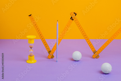 Ruler, hourglass, pencil and golf balls photo