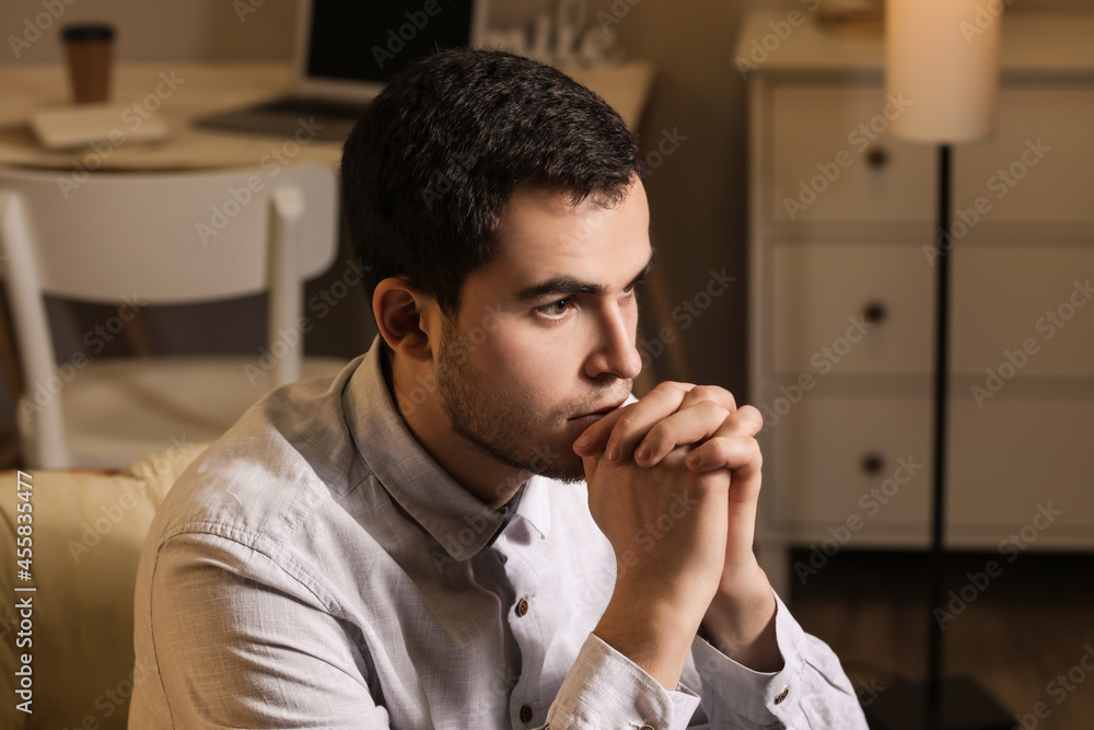 Young man praying at home in evening Young man praying at home in evening