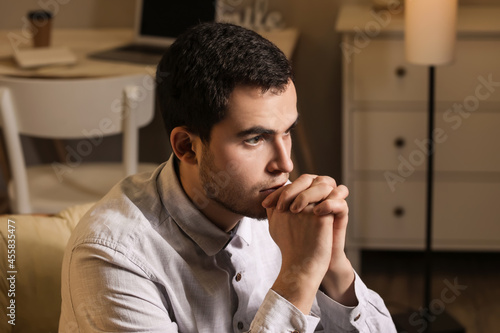 Young man praying at home i...