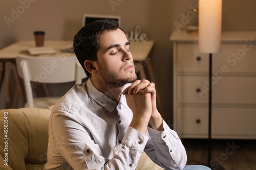 Young man praying at home i...