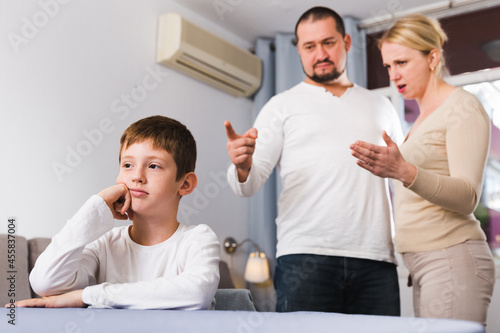 Portrait of upset boy scolded by parents at home