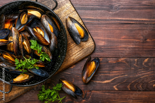 Frying pan with tasty mussels on wooden background, closeup