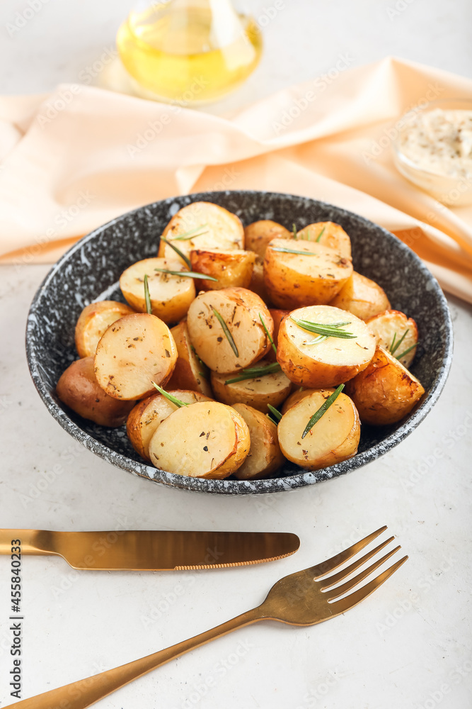 Plate with baked potatoes and rosemary on light background Plate with baked potatoes and rosemary on light background
