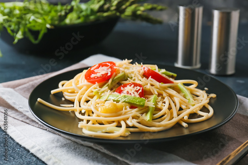 Plate of tasty pasta with vegetables and cheese on dark background