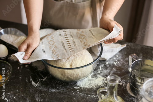 Female chef preparing dough on kitchen table, closeup
