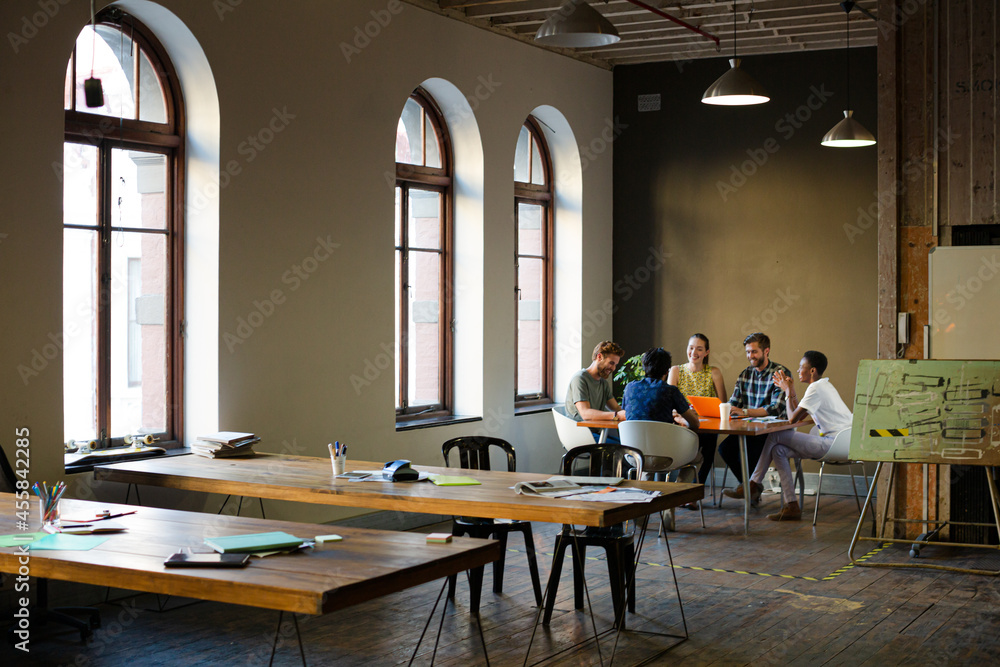 Creative business people working at tables in sunny office Creative business people working at tables in sunny office