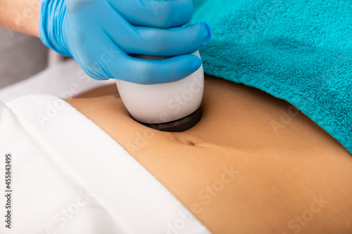 Closeup of needleless mesotherapy hardware procedure to reduce body fat and tighten skin on female belly in aesthetic clinic