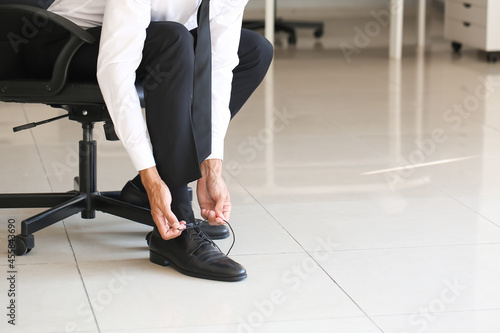 Businessman tying shoe laces in office