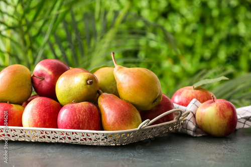 Tray with ripe pears and apples on table outdoors, closeup