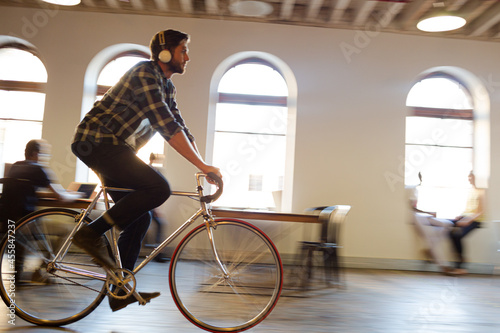 Casual businessman riding bicycle in open office