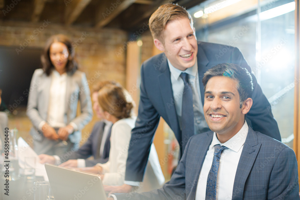 Businessmen smiling at laptop in conference room meeting Businessmen smiling at laptop in conference room meeting