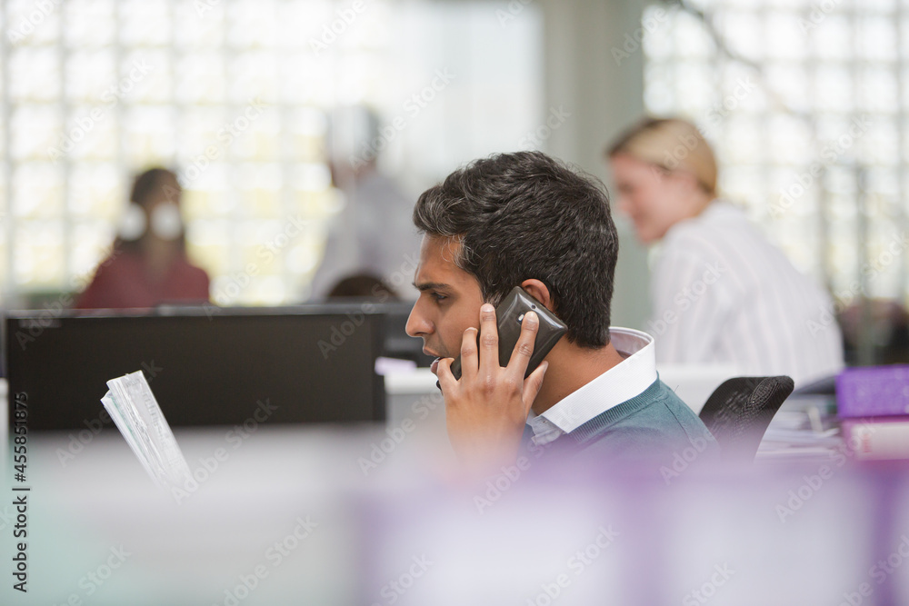 Smiling businessman talking on cell phone in office Smiling businessman talking on cell phone in office