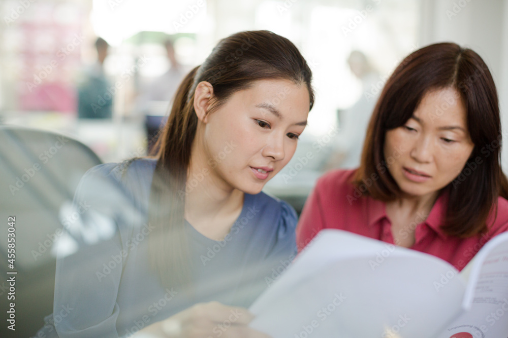 Businesswomen discussing paperwork in office Businesswomen discussing paperwork in office