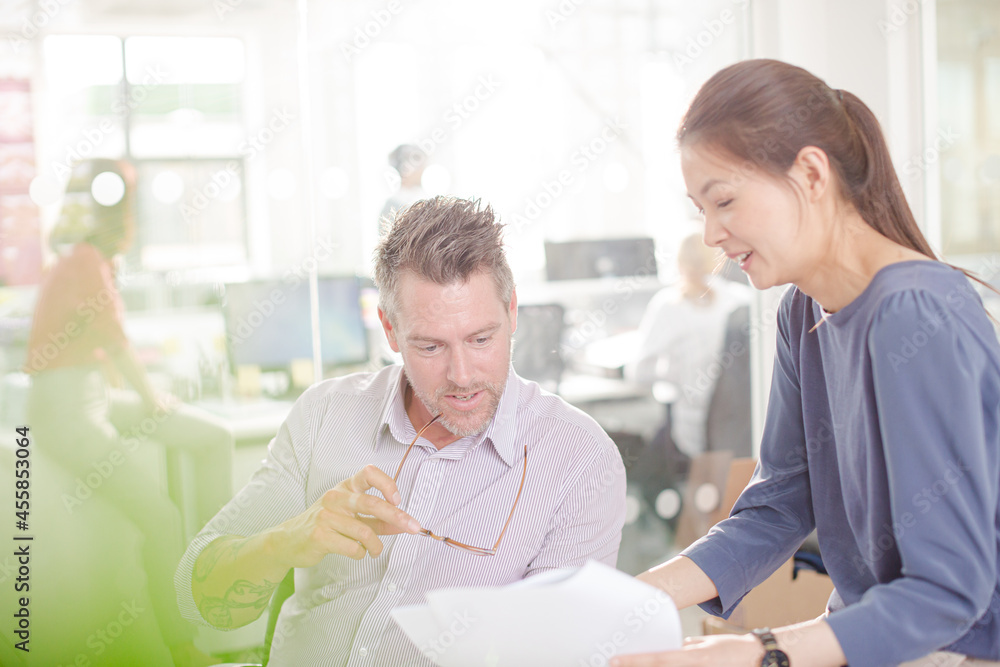 Business people reviewing paperwork at desk in office Business people reviewing paperwork at desk in office
