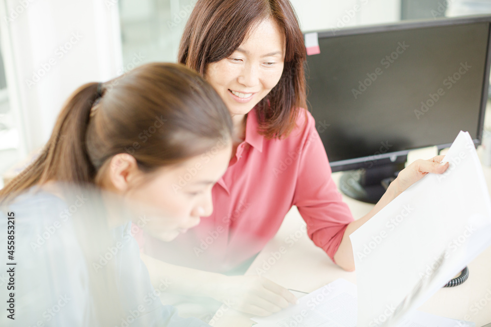 Smiling businesswomen discussing paperwork in office Smiling businesswomen discussing paperwork in office
