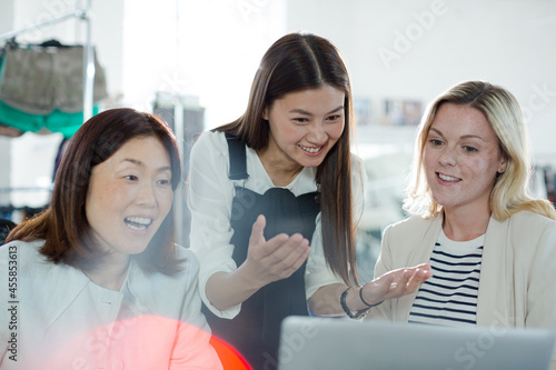 Smiling fashion designers working at laptop in office