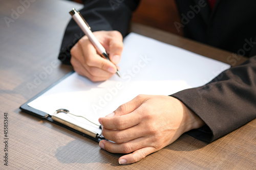 Business man He works on his home office, and he is writing notes on a notebook. In the morning With breakfast on the table