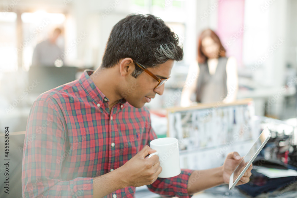 Fashion designer using digital tablet and drinking coffee in office Fashion designer using digital tablet and drinking coffee in office