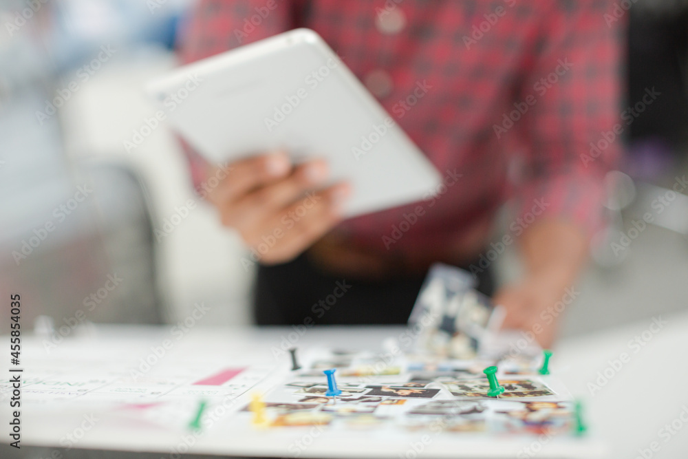 Fashion designer with digital tablet examining story board in office