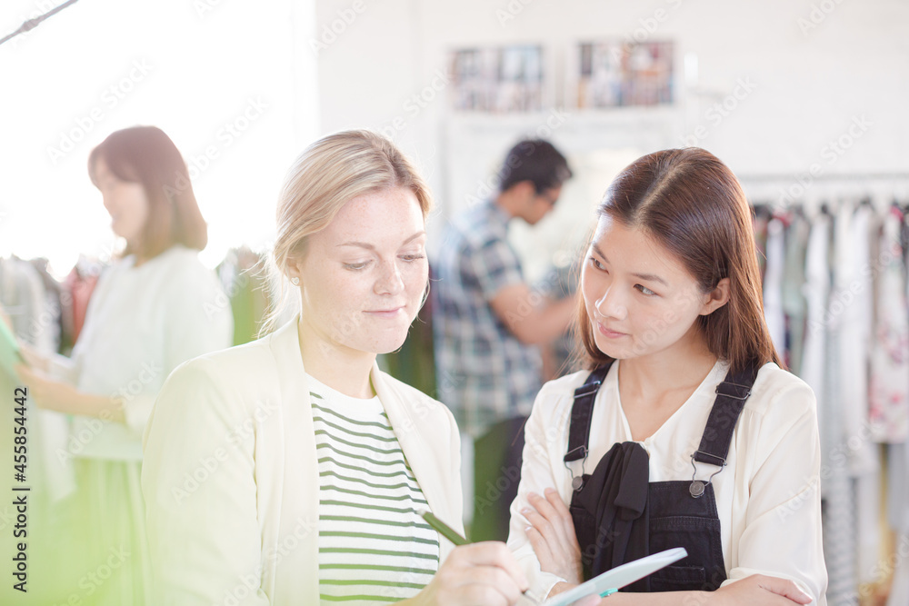 Fashion designer watching assistant taking notes Fashion designer watching assistant taking notes