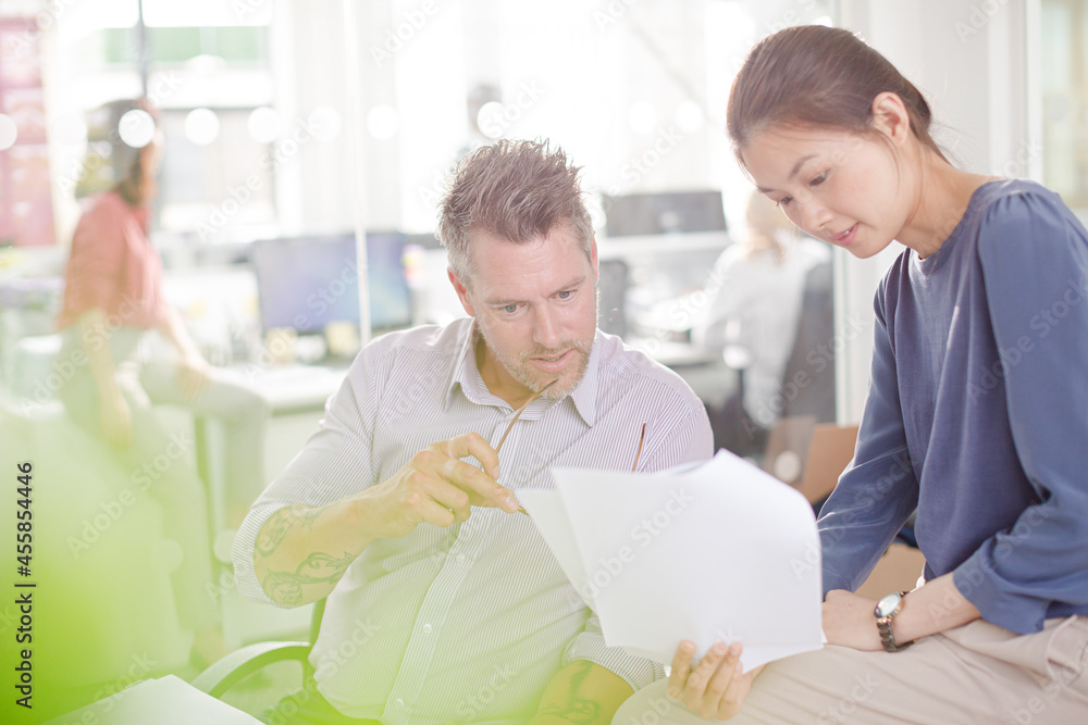 Business people reviewing paperwork at desk in office Business people reviewing paperwork at desk in office
