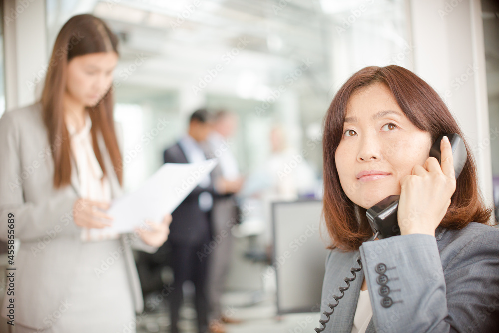 Smiling businesswoman talking on telephone in office Smiling businesswoman talking on telephone in office