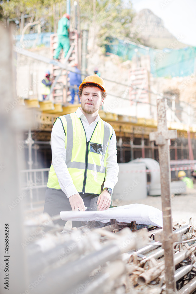 Engineer with blueprints walkie-talkie working at construction site Engineer with blueprints walkie-talkie working at construction site