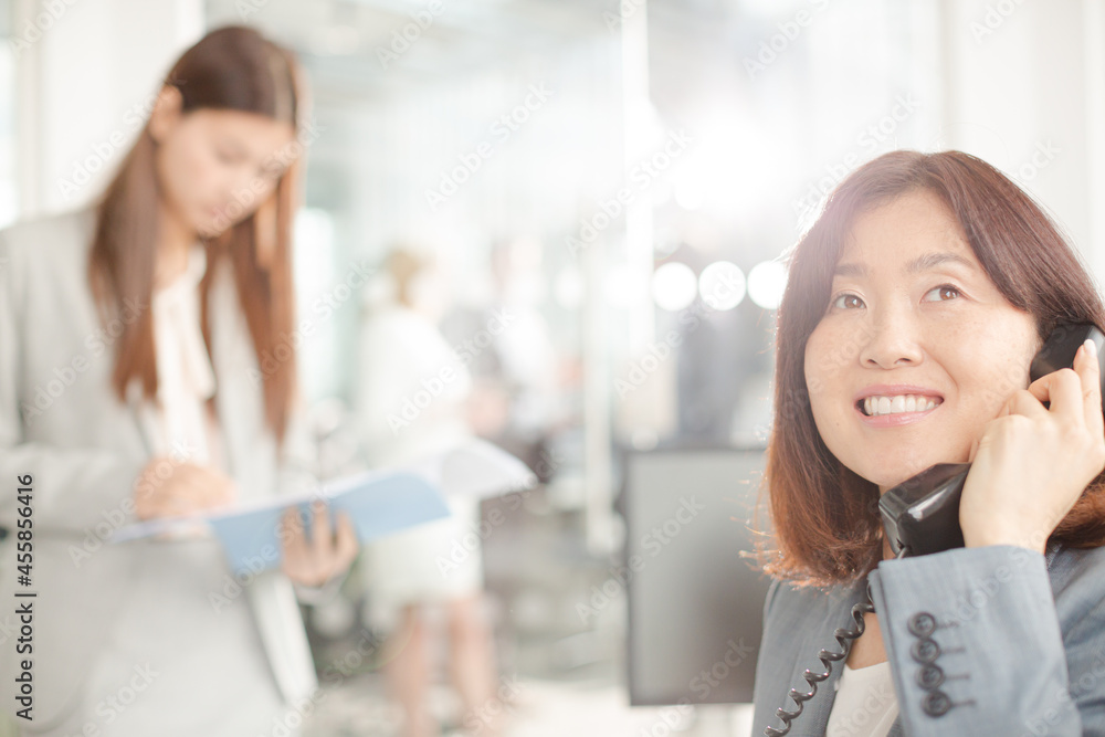 Smiling businesswoman talking on telephone in office Smiling businesswoman talking on telephone in office