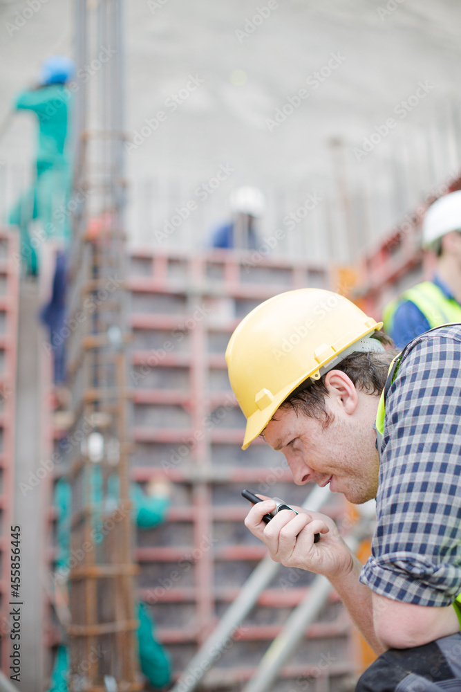 Construction worker with walkie-talkie at construction site Construction worker with walkie-talkie at construction site