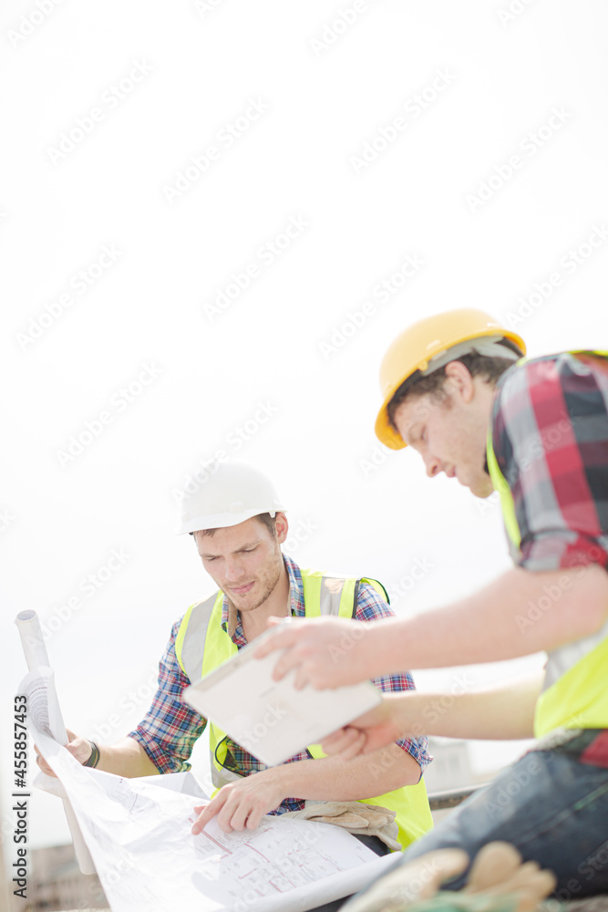 Construction worker engineer reviewing blueprints at highrise construction site Construction worker engineer reviewing blueprints at highrise construction site