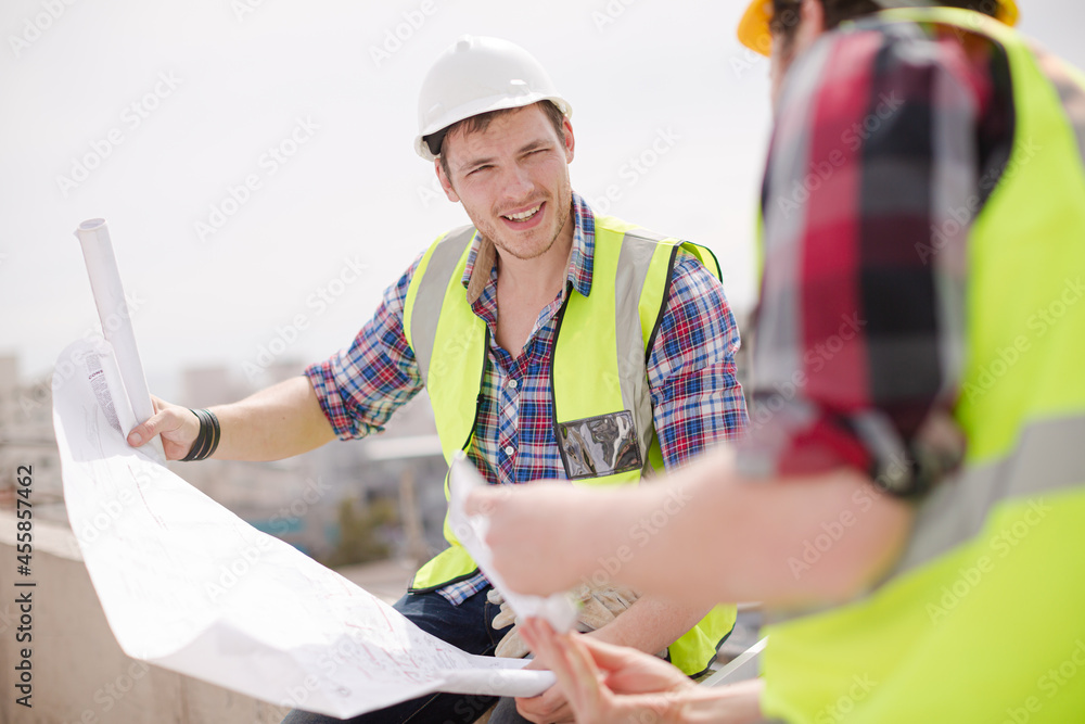Fototapeta premium Construction worker engineer reviewing blueprints at highrise construction site
