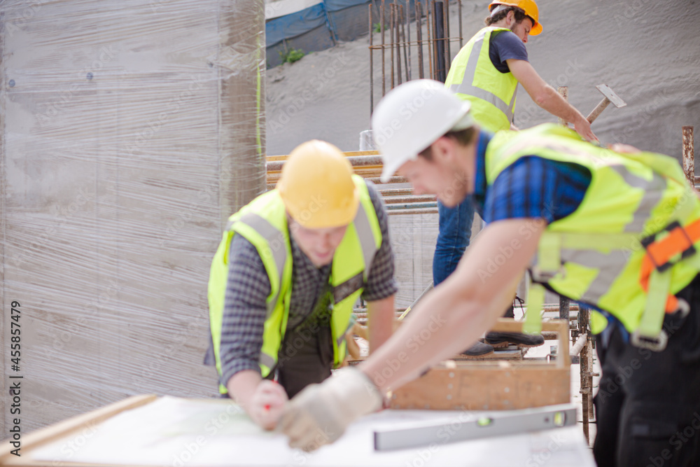 Construction worker engineer reviewing blueprints at construction site Construction worker engineer reviewing blueprints at construction site