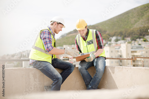 Construction worker engineer clipboard talking at highrise construction site © KOTO