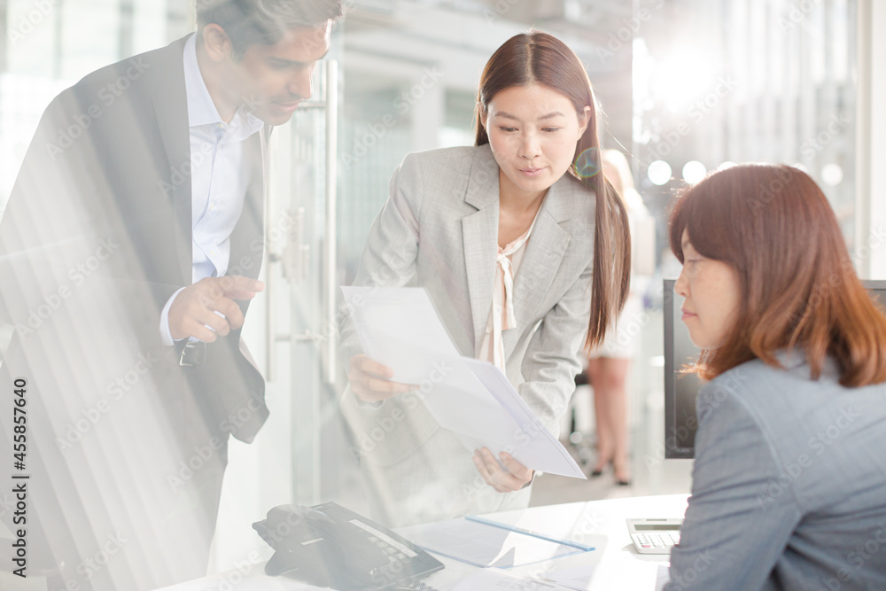 Business people reviewing paperwork at desk in office Business people reviewing paperwork at desk in office