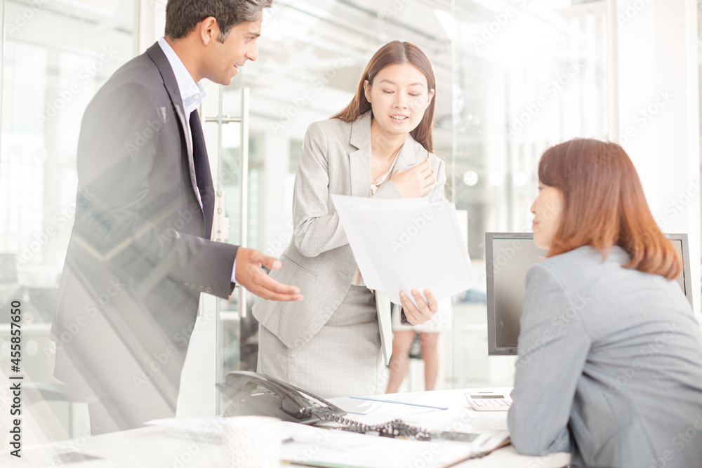 Business people reviewing paperwork at desk in office Business people reviewing paperwork at desk in office