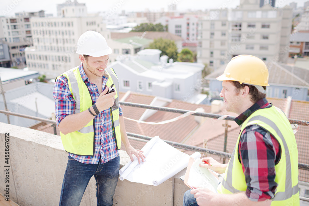 Construction worker engineer reviewing blueprints at highrise construction site Construction worker engineer reviewing blueprints at highrise construction site