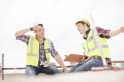 Construction worker engineer clipboard talking at highrise construction site