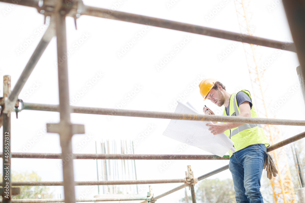 Engineer reviewing blueprints at high rise construction site Engineer reviewing blueprints at high rise construction site