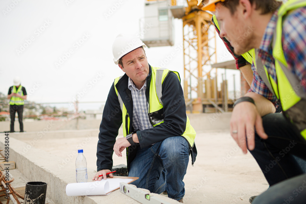 Construction workers using level tool below crane at construction site ...