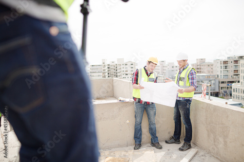 Construction worker engineer reviewing blueprints at highrise construction site © KOTO