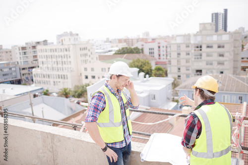 Construction worker engineer reviewing blueprints at highrise construction site