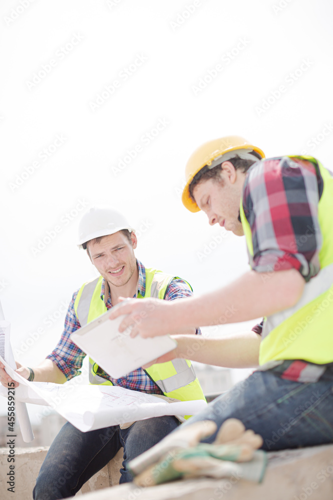 Construction worker engineer reviewing blueprints at highrise construction site Construction worker engineer reviewing blueprints at highrise construction site
