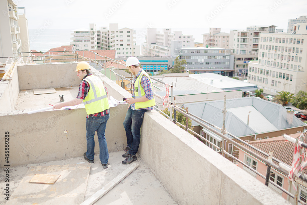 Construction worker engineer reviewing blueprints at highrise construction site