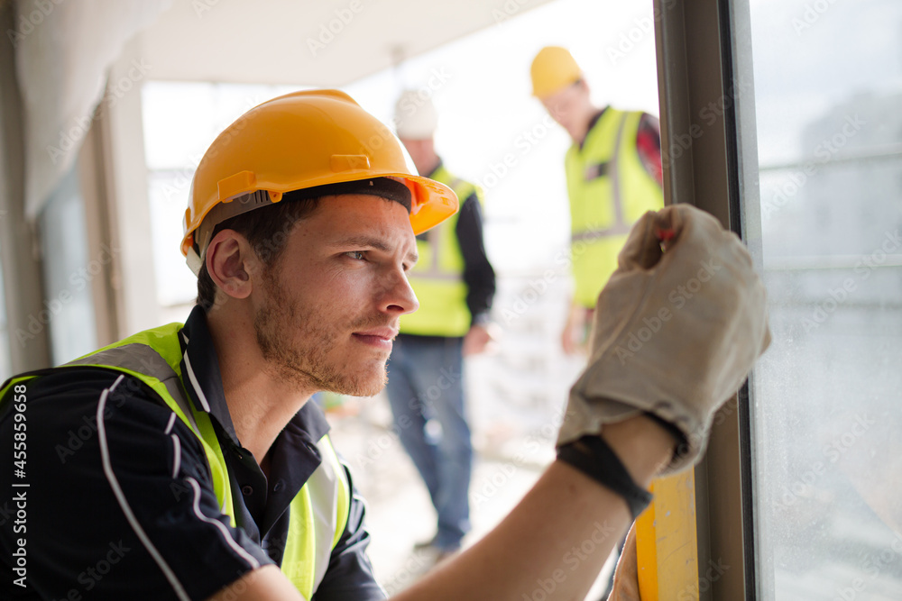 Construction worker measuring window at construction site Construction worker measuring window at construction site