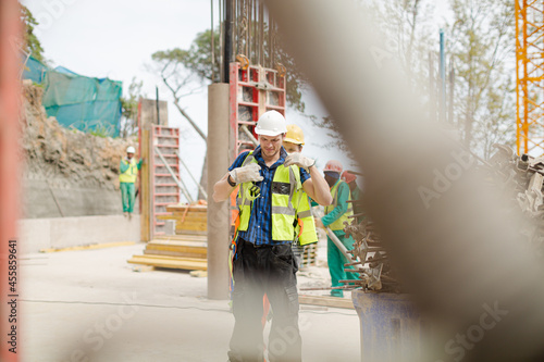 Construction worker fastening coworker‚Äö√Ñ√¥s safety harness © KOTO
