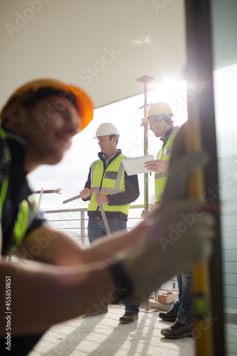 Construction worker measuring window at construction site